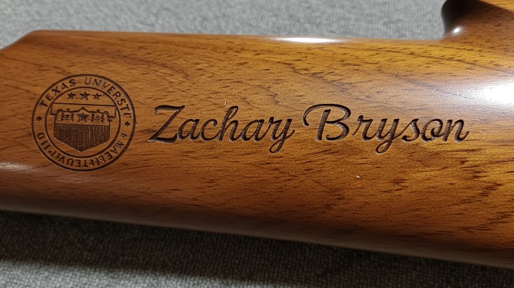 A wooden rifle featuring the engraved name "Zachary Bryson" on its stock