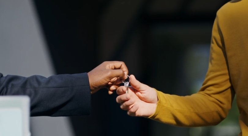 A hand exchanges keys, signifying a transfer of ownership or responsibility
