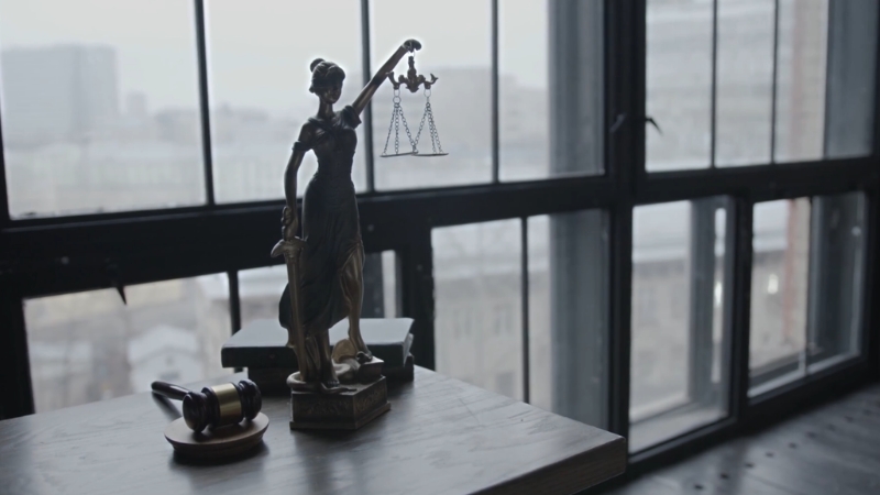 Lady Justice statue and gavel on a desk by a window