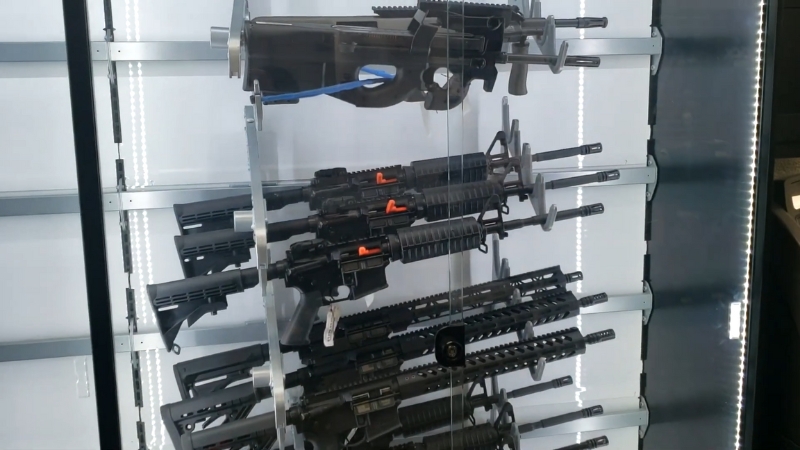 A display case with rifles and carbines securely stored inside a gun shop