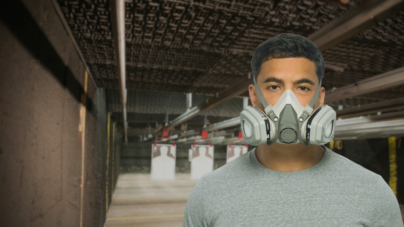 Man wearing a reusable respirator with replaceable filters inside an indoor shooting range
